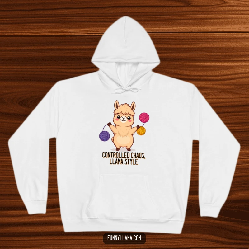 Funny Llama Hoodie showcasing a fuzzy brown llama with a big grin, actively juggling colorful yarn balls in a comical scene.